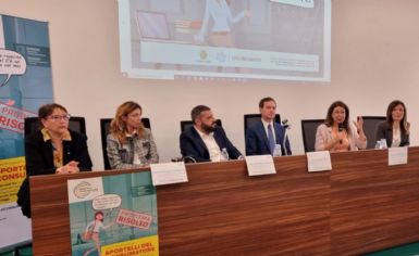 Foto della conferenza con i partecipanti schierati dietro al tavolo