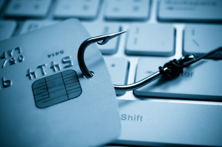 Immagine di una carta di credito infilata in un amo da pesca, sullo sfondo una tastiera per computer