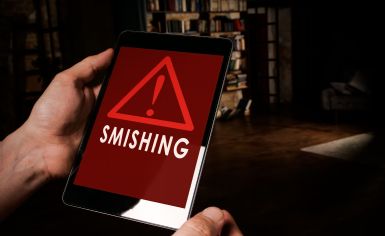 Foto di un tablet con sullo schermo un triangolo di avviso rosso e la scritta SMISHING